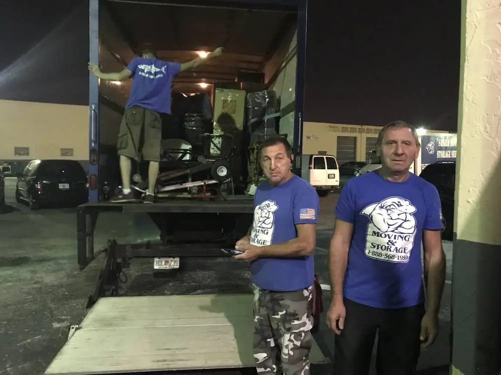 two men standing in front of a moving truck.