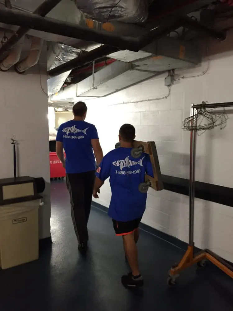 Two people in blue shirts walking down a hallway.